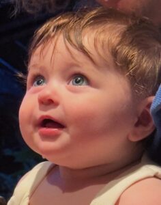A baby looks expectantly upward