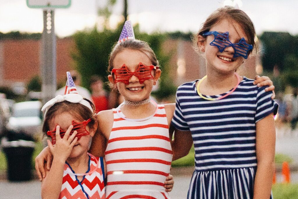 Children in festive attire celebrating Fourth of July with smiles and fun.